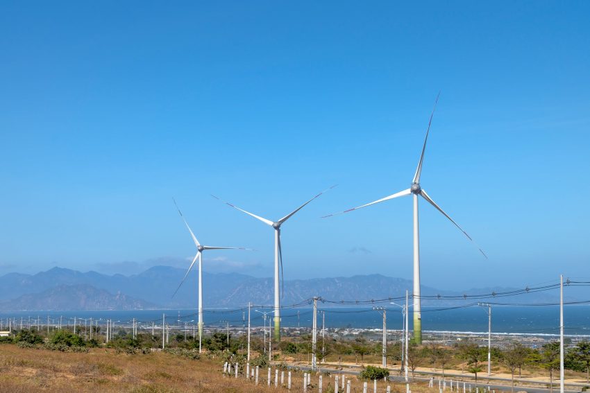 windmills against sea and ridges under blue sky