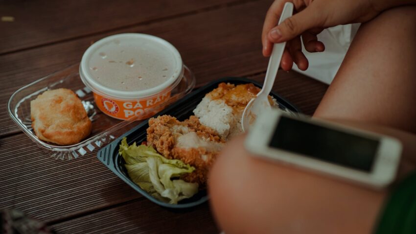 person holding white disposable spoon eating fried chicken